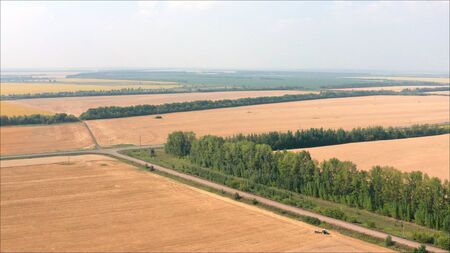 Harvester machine working in field . Combine harvester agriculture machine harvesting golden ripe wheat field. Agriculture. Aerial view. From above. Beautiful field with wheat.の写真素材
