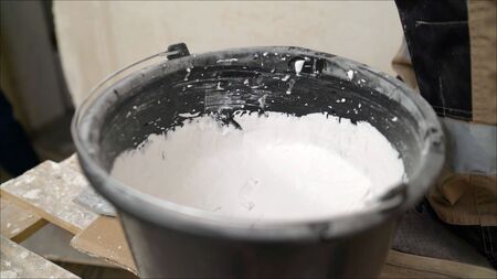 white putty cement in black bucket on floor for rebuild wall at home - can use to display or montage...