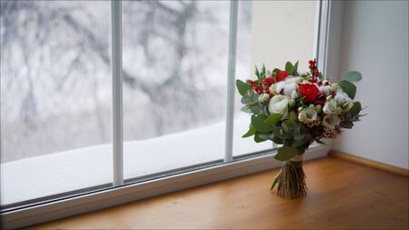 bright red wedding bouquet of fresh flowers and eucalyptus stands on the windowsill. Beautiful wedding bouquet on the windowsill.の写真素材