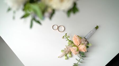 Wedding rings and boutonniere. Wedding boutonniere and wedding rings on brown clothの写真素材