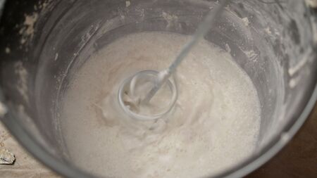 Mix the storing solution in a bucket. Putty in a bucket.Mixing plaster solution in a bucket, using...