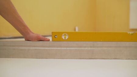 A worker checks the floor level using a tool level. Smooth White Floor Test Tool