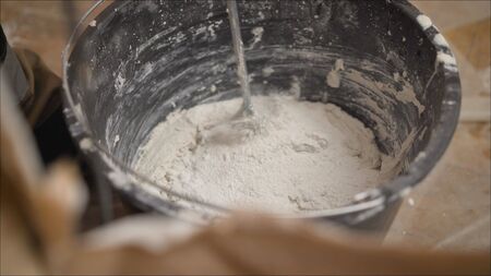 Worker interferes with mortar in a bucket. Plasterer painter interferes with the mixture for the wallsの写真素材