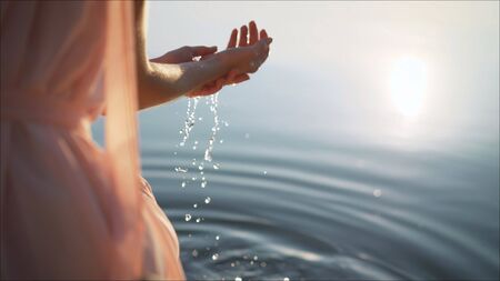 Beautiful female hands on a wild brook. Feminine hands with spring waterの写真素材