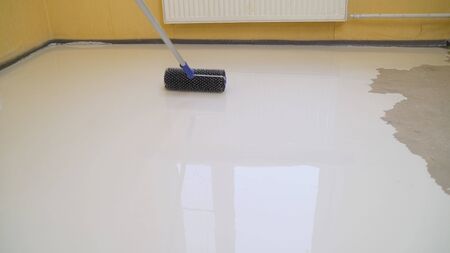 Self-leveling flooring. Mirror smooth floor surface. Roller application. leveling the floor with a roller. The interior of the apartment is under construction.の写真素材