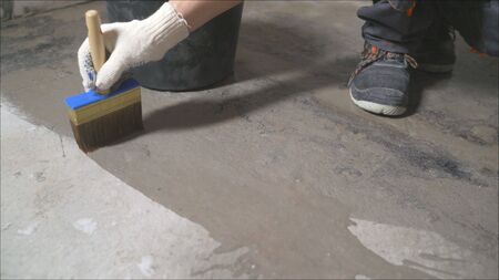 Primer concrete floor for waterproofing. Worker wets the concrete floor with a brush.の写真素材