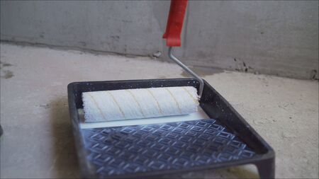 A roller in the bathroom interferes with putty. White putty is stirred. the roller dip into the...