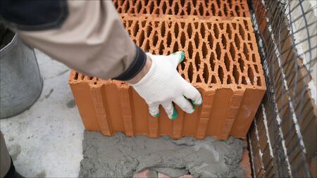 Builder smears a mortar under a brickBuilder's hands with putty knife, add. Work on laying a building block. builders are laying a ceramic block.の写真素材