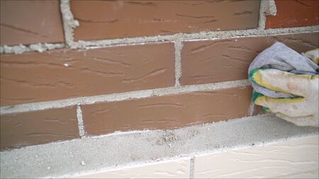 Brick house construction. Worker wipes the seams in the brickwork. Worker rewrites a brick wall.の写真素材