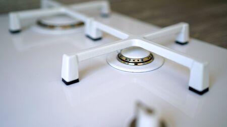 Macro closeup of modern luxury gas stove top with tiled backsplash. White modern gas stove