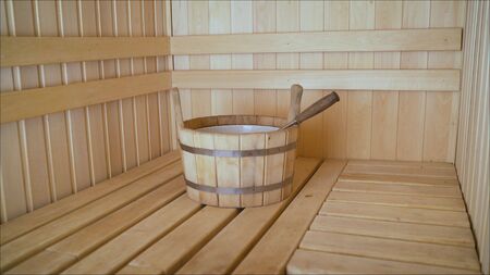 Steam room in a Finnish bath with a wooden basin with water for soaking. Sauna with a wooden basin.の写真素材