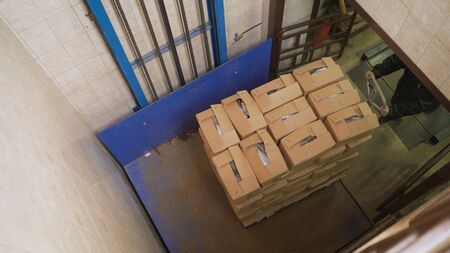 Boxes rise on the elevator. Fish factory, unloading fish. Crates of fish rise on the elevator.