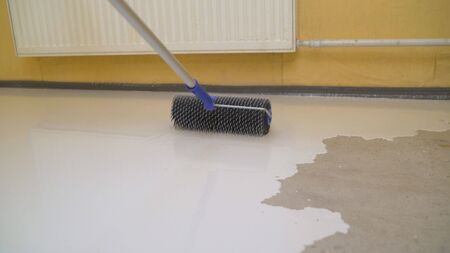 Contract painter painting garage floor to speed up selling of home. Concrete floor pouring special Fillable mortar. Self-filling floor.の写真素材