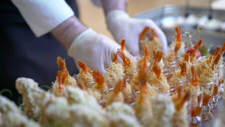 Catering. The waiter lays out snacks. off-premise catering - waitresses put fruit canapes on buffet tableの写真素材