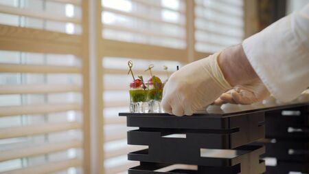 Catering. The waiter lays out snacks. off-premise catering - waitresses put fruit canapes on buffet...