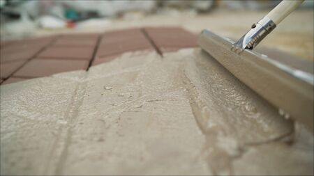 Worker makes paving slabs.. poorly laid pavement tiles on a walkway in the park