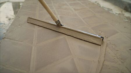 Filling glue on the road tile.. Road tile with mortar. Worker hand with bucket pouring cement for tiles installation making on floorの写真素材