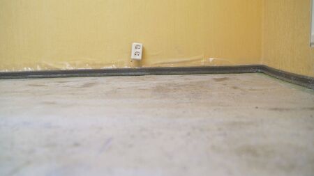 The worker primed the floor with a white primer. apartment repair. Fill the floor. Primed floor in the room.の写真素材