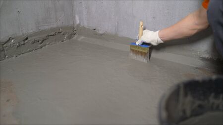 The master puts waterproofing on a concrete floor with a brush. Waterproofing concrete mortar.の写真素材