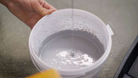 The white paint is mixed in a bucket with a drill. Drill paddle mixer on a bucket with white paint, DIY tools and accessory, bannerの写真素材
