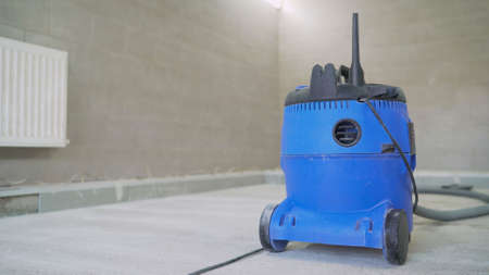 Industrial vacuum cleaner for collecting construction dust and debris. Professional vacuum cleaner after work. Blue construction waste collection tankの写真素材