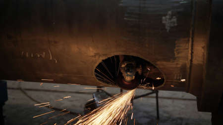 Work grinder cuts metal at the factory. Heavy industry worker cuts a huge pipe