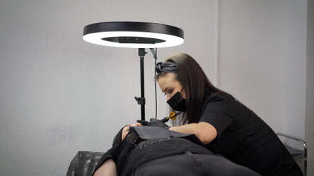 Brow master measuring brows with the ruler. Permanent makeup for eyebrows in beauty salon. The master applies permanent makeup.の写真素材