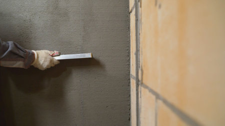 The builders are using triangular steel to smooth the plaster evenly in the walls of the house. concepts of the construction industry with skilled workers. The craftsman evens the putty on the wall.の写真素材
