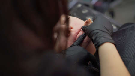 Permanent make up procedure, applying on young girl.Close-up.Young beautiful woman making permanent...
