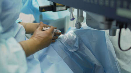 The doctor uses a syringe to instill the pain reliever into the patients eye. It drips from the syringe into the eye. Doctor with syringe eye surgery. treatment of a cataract by a surgical method.の写真素材