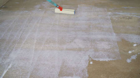 Priming the concrete floor with a roller. Professional floor primer. Leveling concrete floors. Floor repair using a primer.の写真素材