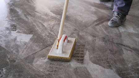Worker washing tiles after work. A worker washes the tiles on the floor after grouting.の写真素材