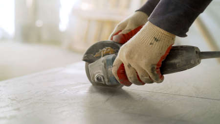 The tiles are cut with a special saw for a perfect fit. A craftsman saws ceramic tiles.の写真素材