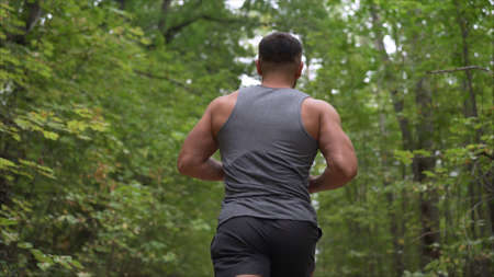 Running through the morning forest. The guy is running through the forest. The athlete runs through the autumn forest.の写真素材