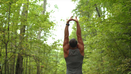 A handsome, hard-working man is standing in a field. Athlete in the forest.の写真素材