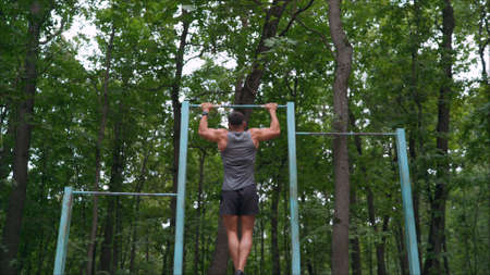 Closeup of strong athlete doing pull-up on horizontal bar.Mans fitness with blue sky in the...