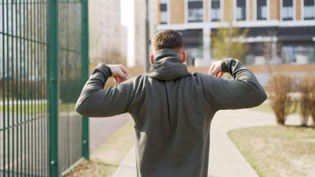 Man doing warm-up before strength training outdoors on green grass. The athletic guy walks and warms up before training. Warm up before training outdoors.の写真素材