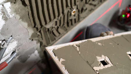 A worker smears ceramic tiles for laying. Laying ceramic tiles on the floor. Ceramic tile. The tiler...