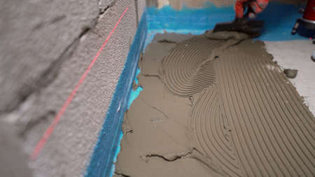 A worker smears ceramic tiles for laying. Laying ceramic tiles on the floor. Ceramic tile. The tiler...