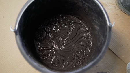 Mixing of mortar concrete mixture, using an electric drill, for bonding ceramic tiles. Black tile...