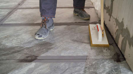 Laying floor tiles, tiler cleaning tiles after filling up joints. Cleaning tiles after laying on the floor.の写真素材