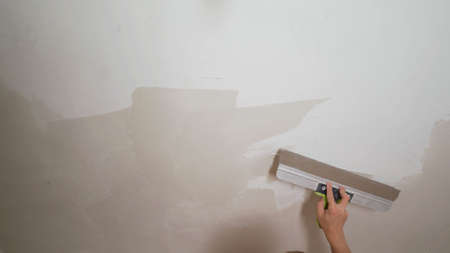 The process of applying putty with a spatula. Putty on the concrete wall with a metal trowel. The...