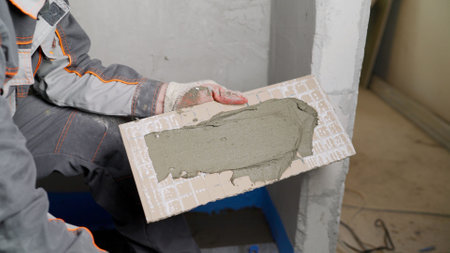 The process of laying ceramic floor tiles with a herringbone pattern. spreading mortar on a ceramic...