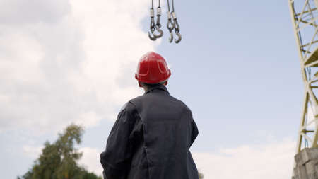 House construction inspection. A worker in a helmet against the background of a tower crane.