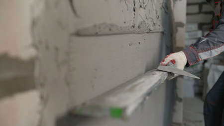 The process of leveling plaster according to the rule after application by machine. A builder uses a...