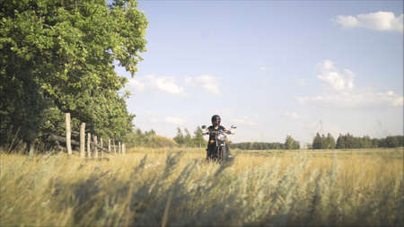 Motorcyclist rides on the field. The concept of adventure. Motorcyclist rides on a country road in...