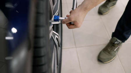 The master tightens the wheels in the auto repair shop, close-up. Auto mechanic repairs car tires....