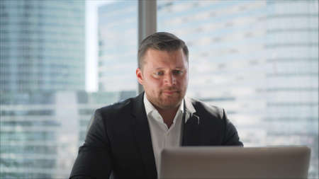 A businessman in a posh office works at the table. Businessman in an office with a panoramic city...