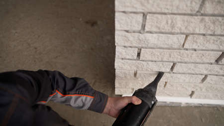 The process of applying a primer to a wall using a roller. Application of glue with a roller on the wall under the ceiling. Filling joints in brickwork. Bricklayer filling joints in the brick wall. Pointing joints in the brick wall.の写真素材
