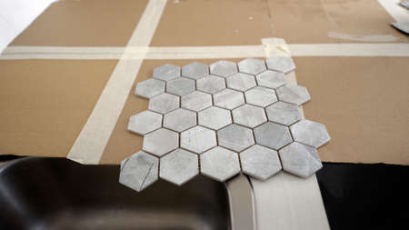 Mosaic ceramic tiles lie on the table. Ceramic tile - mosaic. Ceramic tiles for the kitchen, grey.